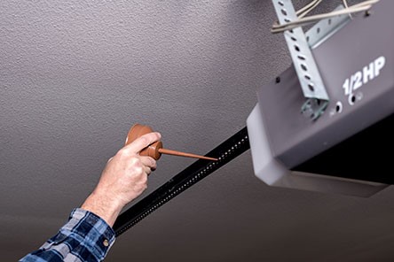 A man hand troubleshoots garage door